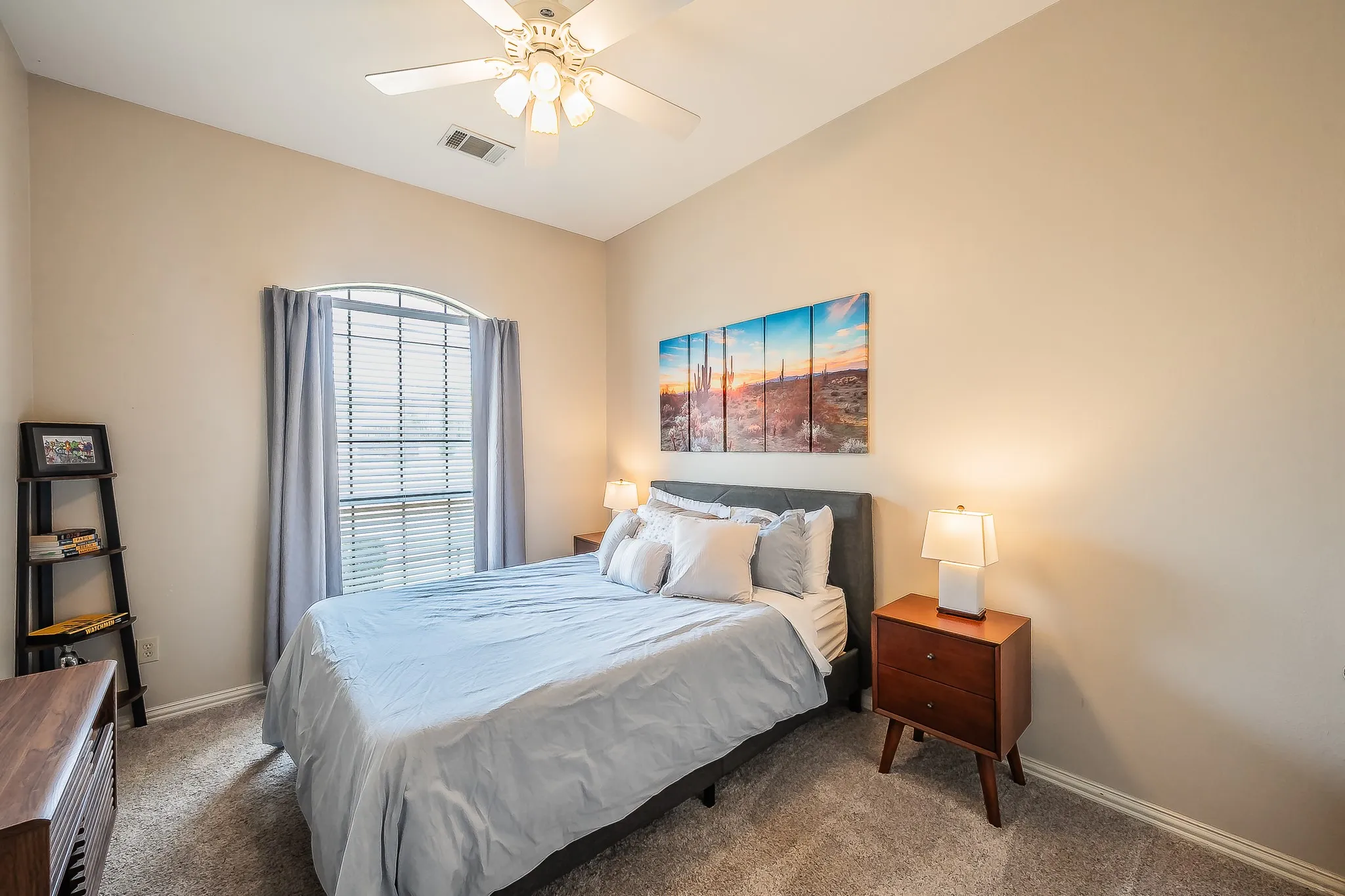 Arched window with blinds, ceiling fan with light fixture, neutral wall color, and carpeted flooring
