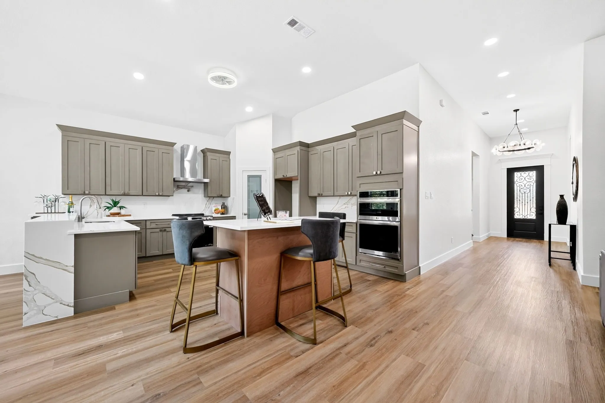Modern kitchen with light wood-finish flooring, two large kitchen islands, and built-in stainless steel appliances