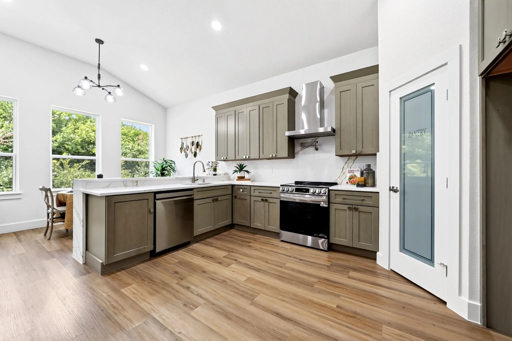 Kitchen featuring wood-finish flooring, white vaulted ceiling, recessed lighting, and a glass-paneled pantry door
