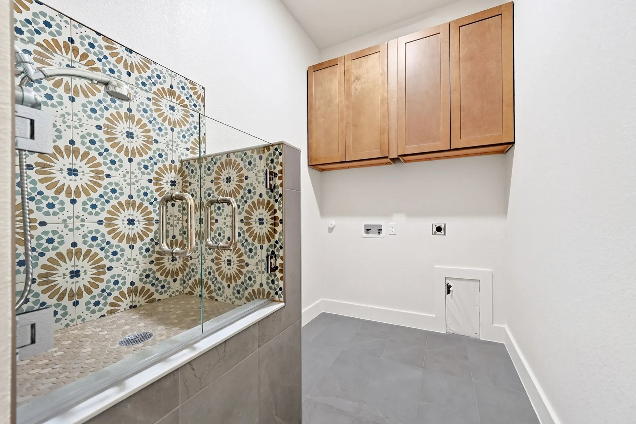 Glass-enclosed shower with decorative tile surround and floor, complemented by a floor-level pet access door