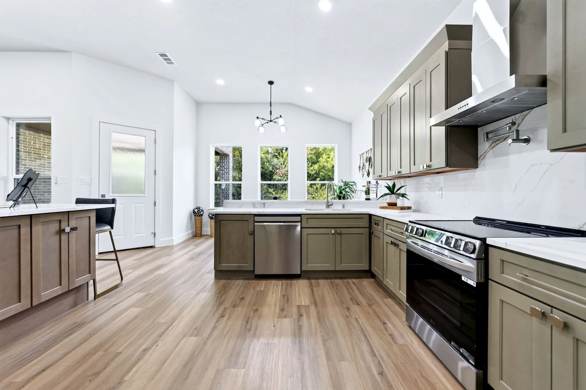 Vaulted ceilings, wood-finish flooring, stainless steel appliances, modern cabinetry, and white countertops