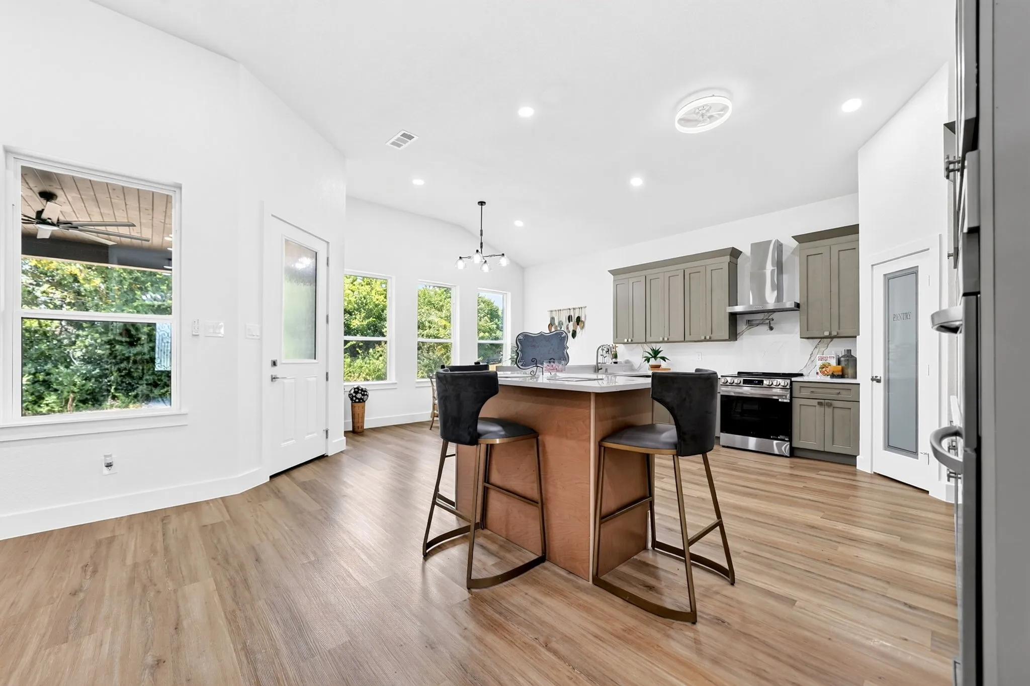 Kitchen featuring an island with a light wood base, gray perimeter cabinetry, stainless steel appliances, and wood-finish flooring