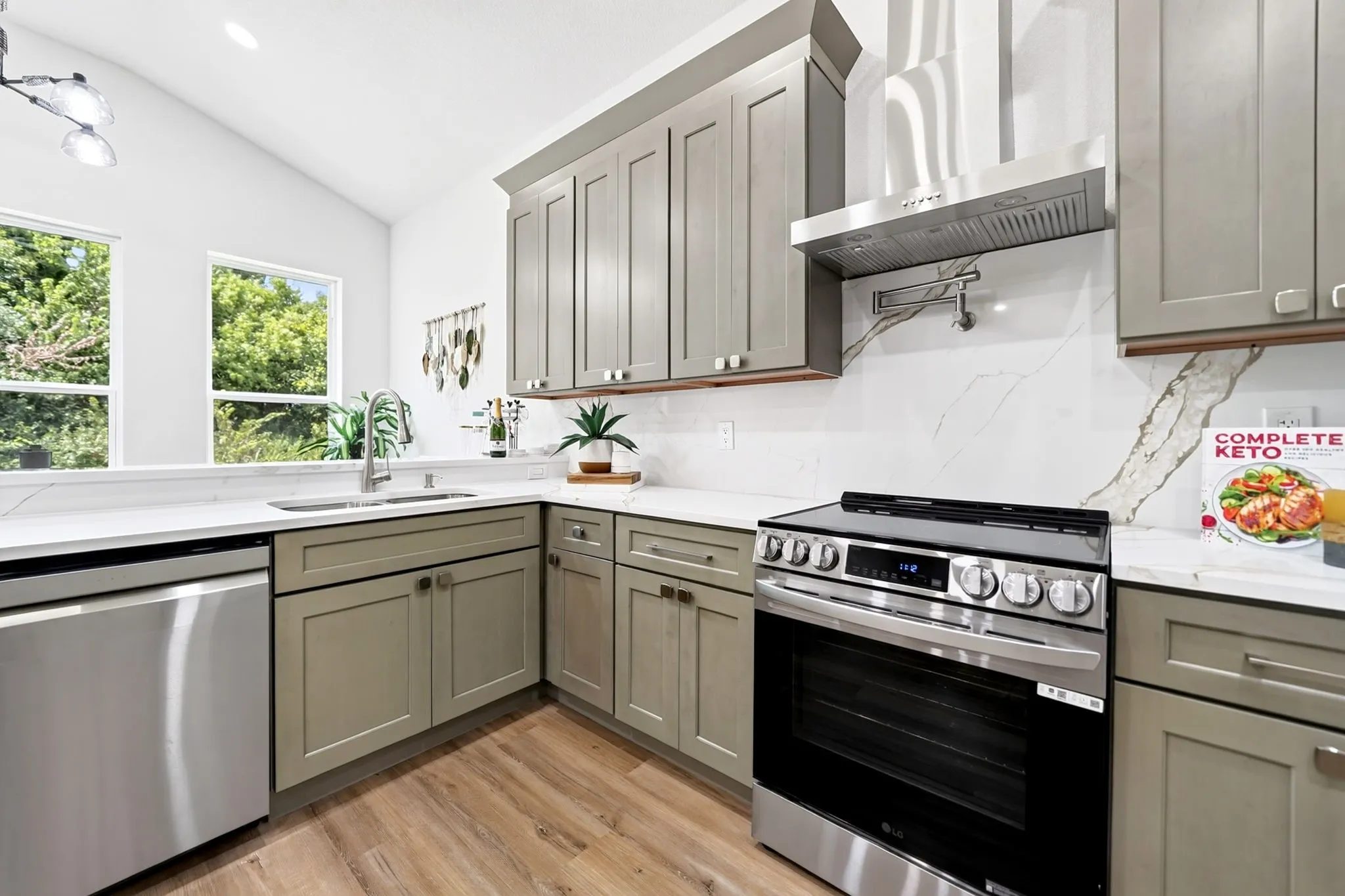 Kitchen featuring stainless steel appliances, light-colored cabinetry, white countertops, a contrasting backsplash, and wood-finish flooring