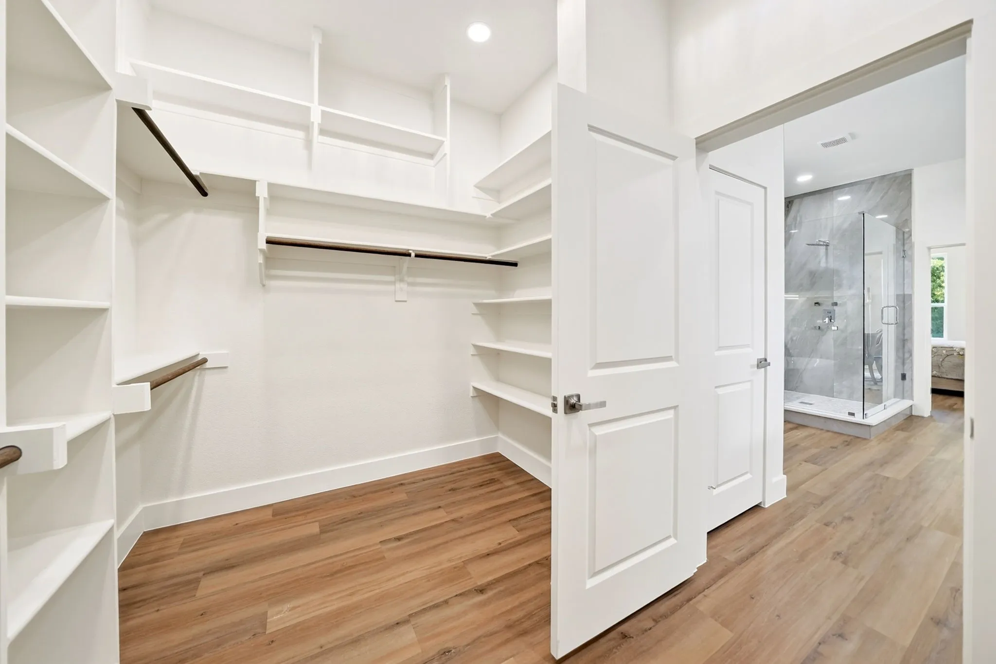 Walk-in closet with built-in shelving, hanging rods, and wood-finish flooring