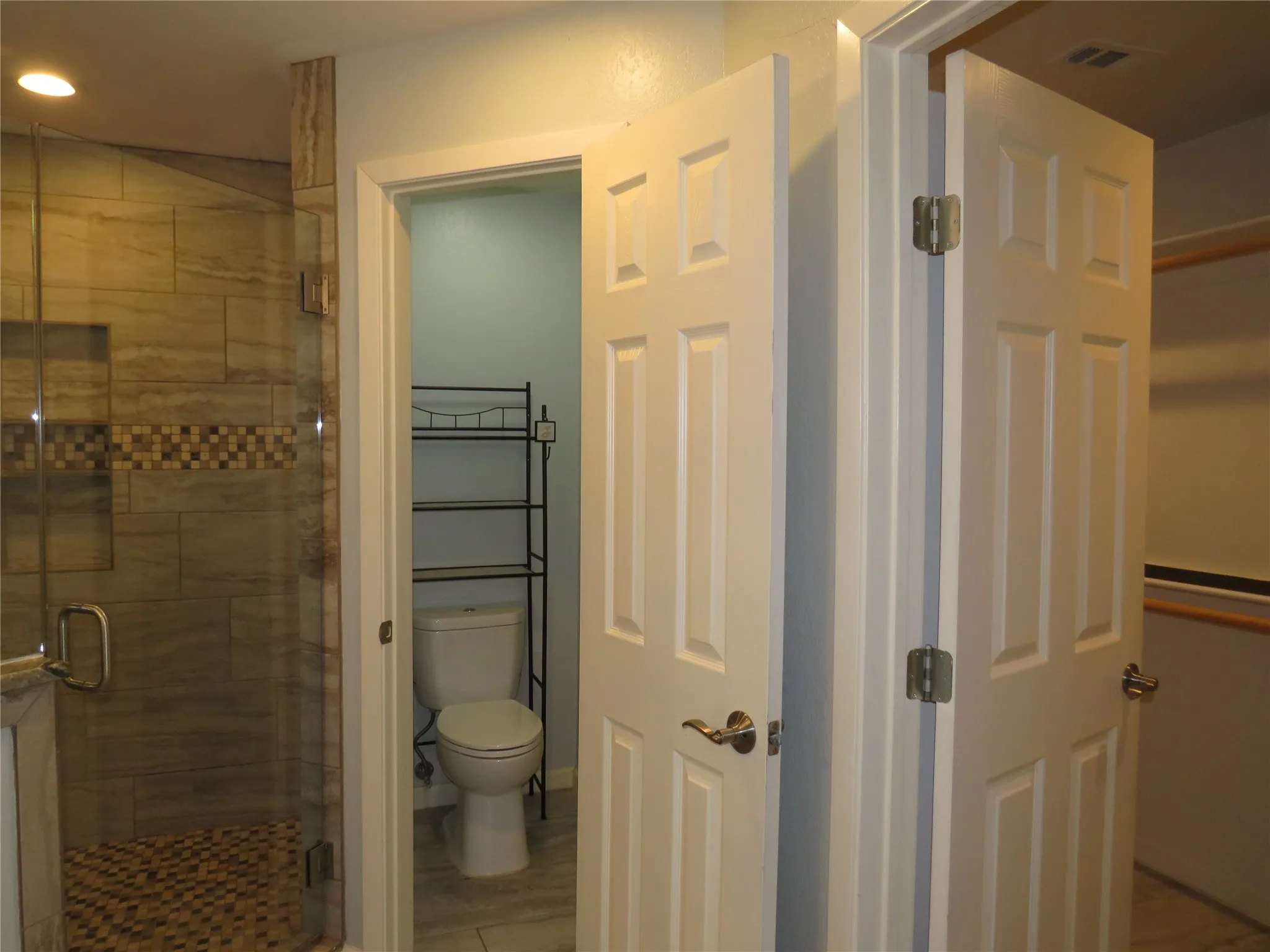 Glass-enclosed shower with tiled walls and a mosaic accent band