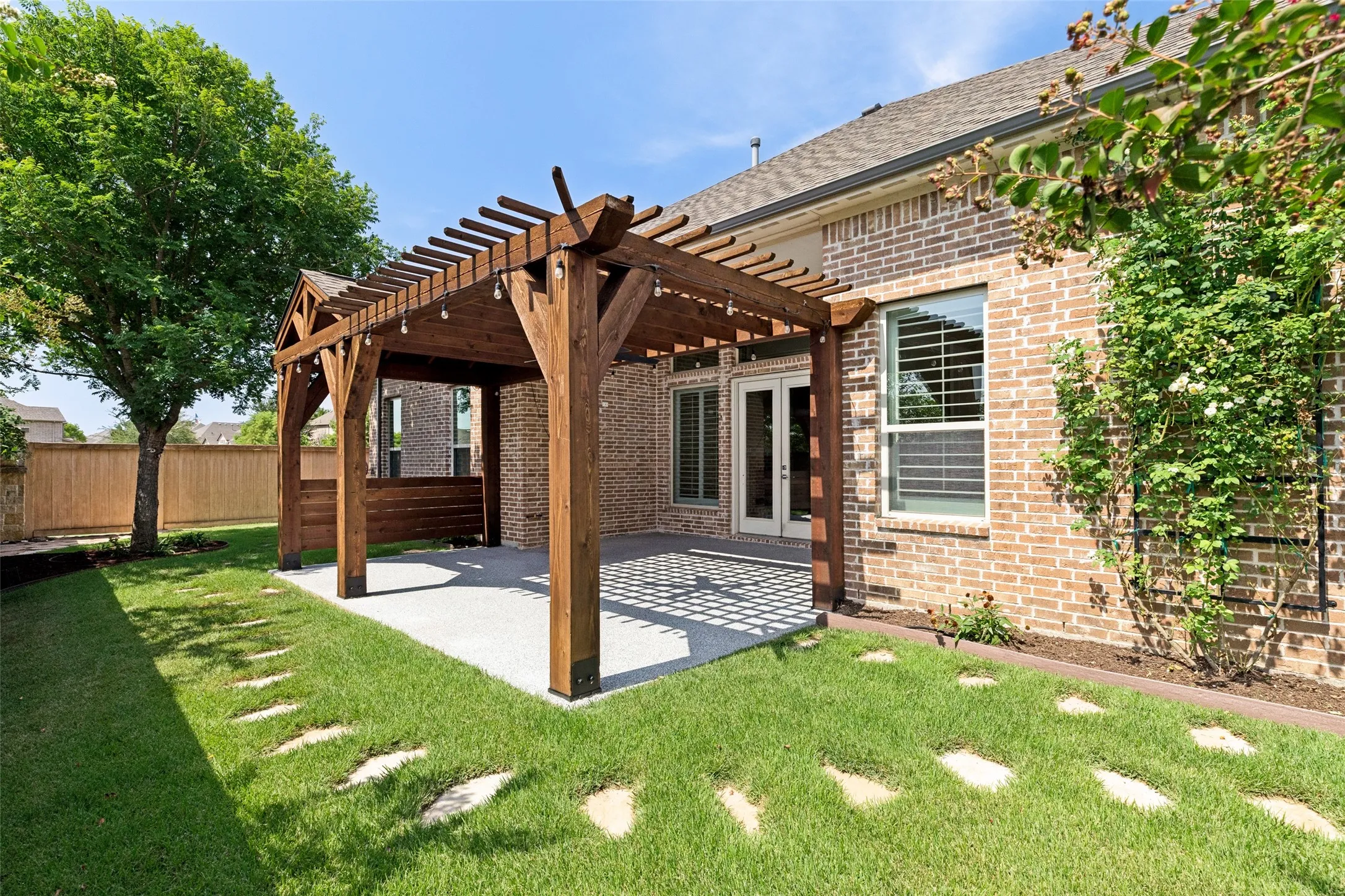 Brick exterior with a wood pergola covering a concrete patio