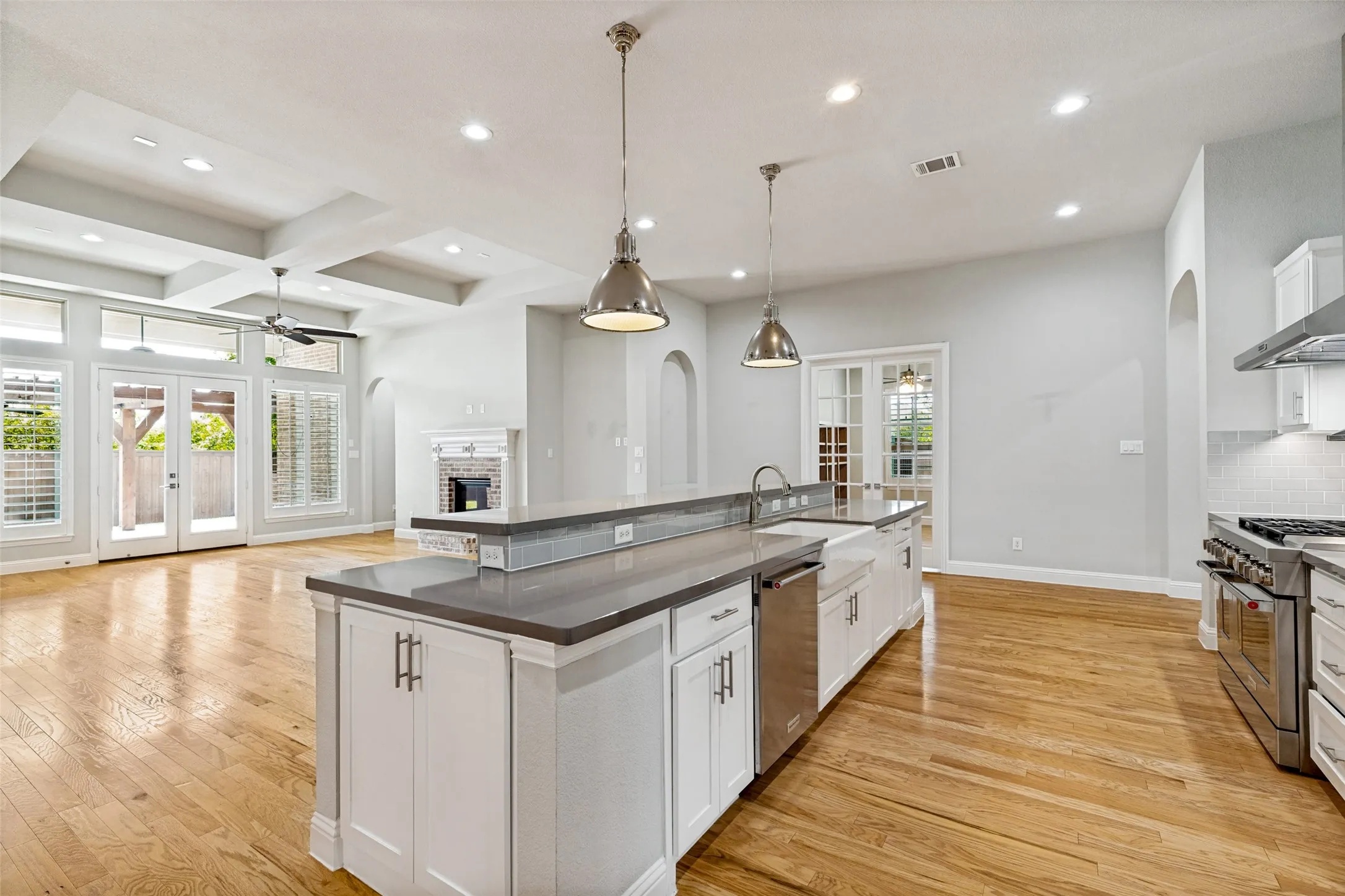 Open-concept kitchen with a large island, stainless steel appliances, and a farmhouse-style sink