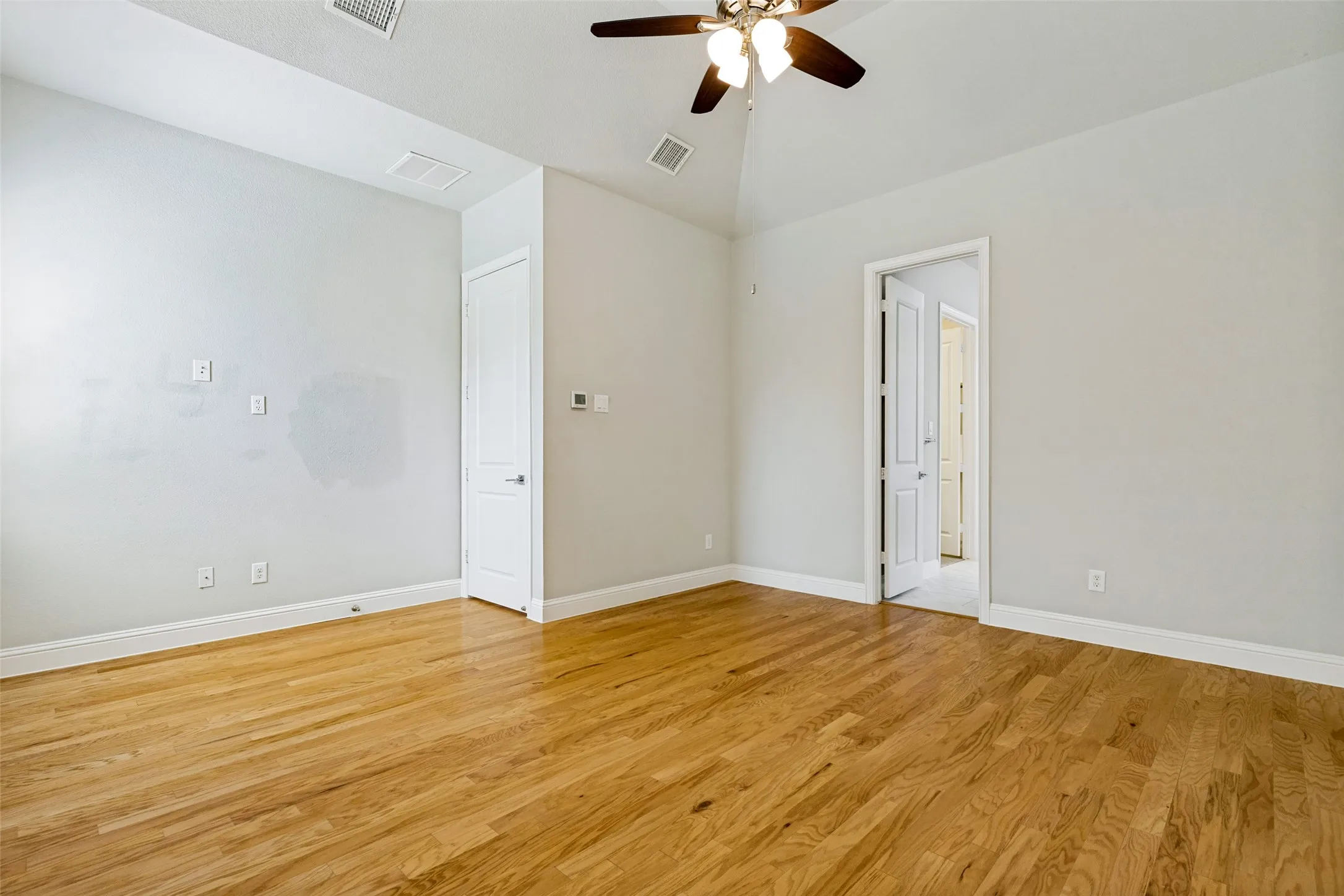 Hardwood flooring with a natural finish, vaulted ceiling, and ceiling fan with integrated lighting