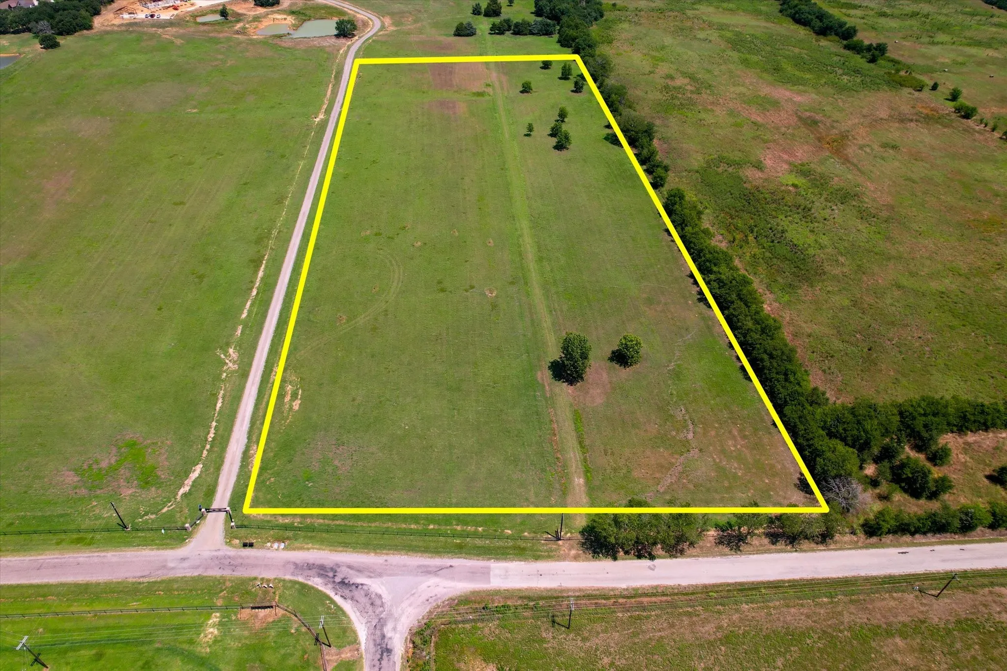 Expansive rectangular parcel featuring approximately 10+ acres of cleared, level land with mature tree clusters and established property boundaries