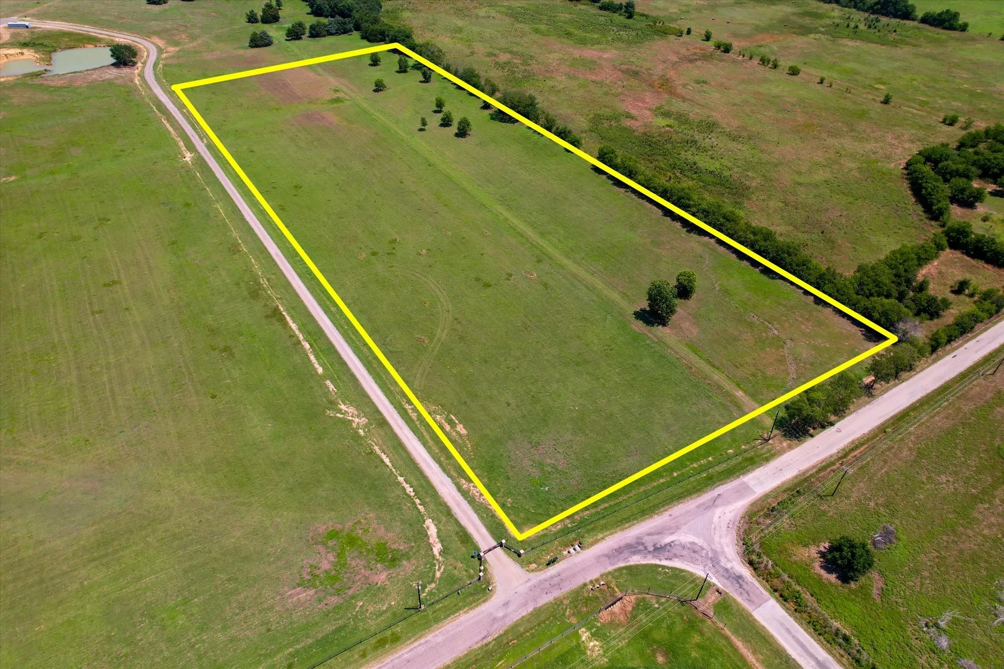 Expansive vacant land parcel featuring approximately 40+ acres of open grassland with mature tree clusters scattered throughout