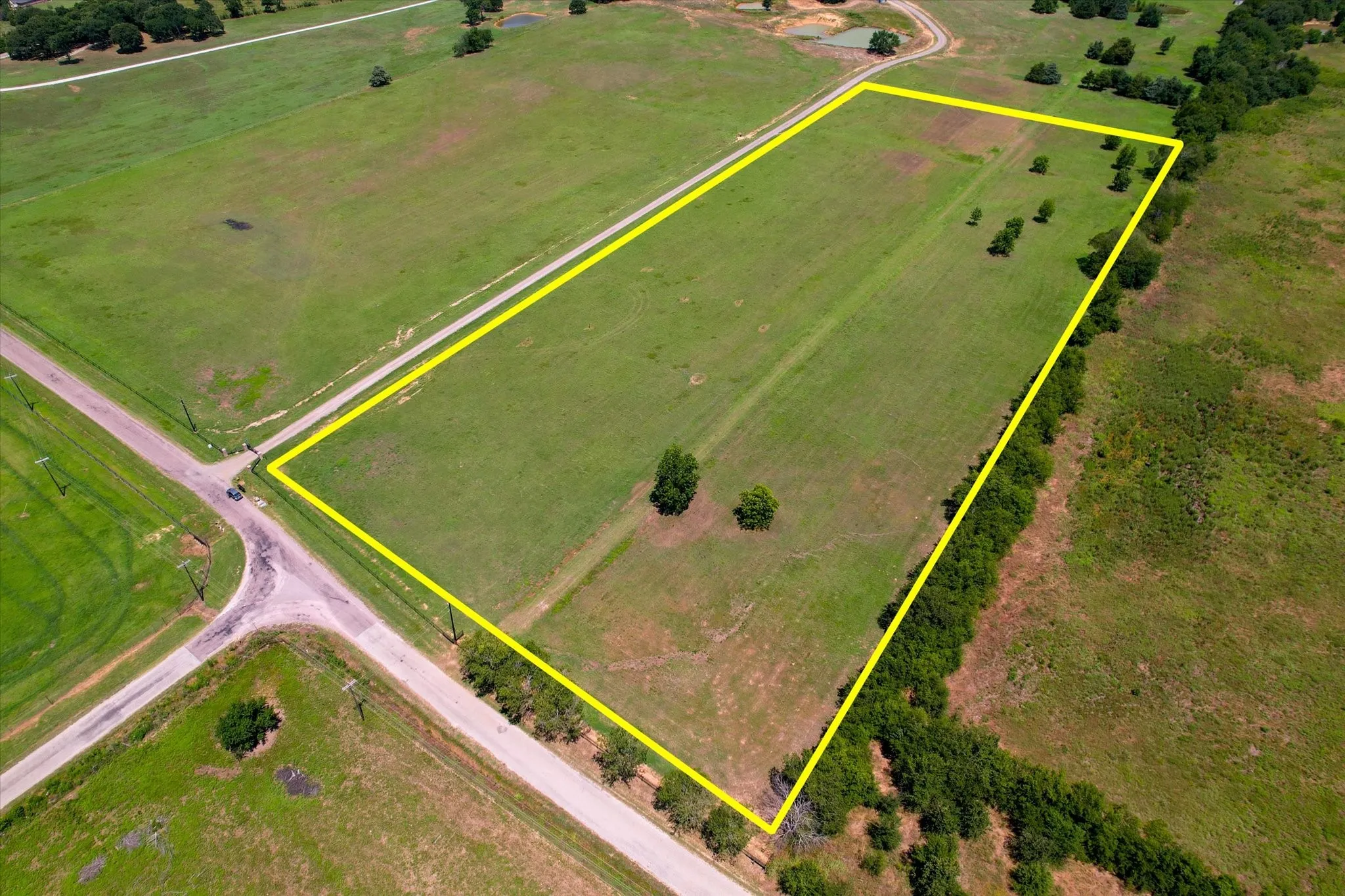 Expansive vacant land parcel featuring approximately 40+ acres of open grassland with mature tree clusters positioned throughout