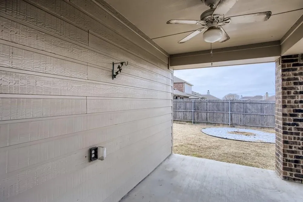 Covered patio with a ceiling fan, concrete flooring, and an exterior electrical outlet