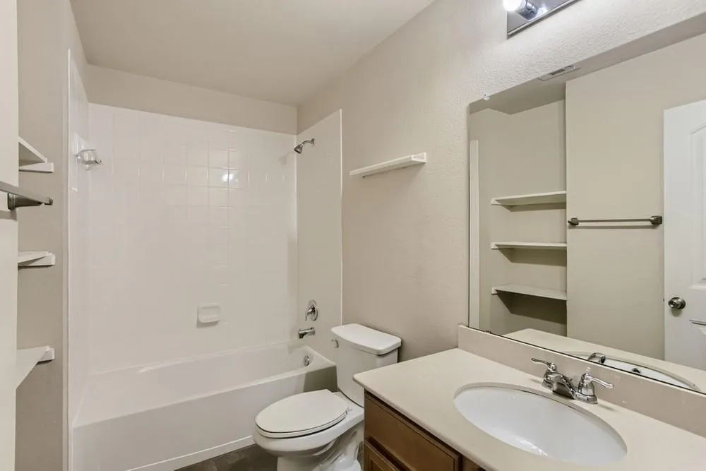 Bathroom featuring a white bathtub with subway tile surround, single vanity with an integrated sink, and an overhead light fixture