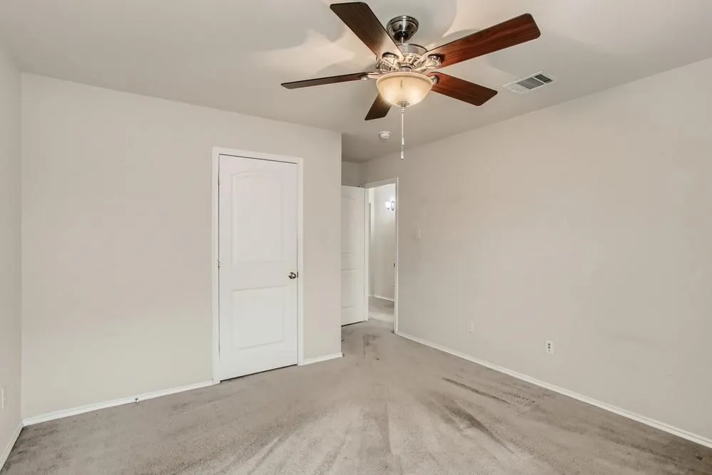 Light grey carpeted flooring, neutral wall tones, and a ceiling fan with light fixture