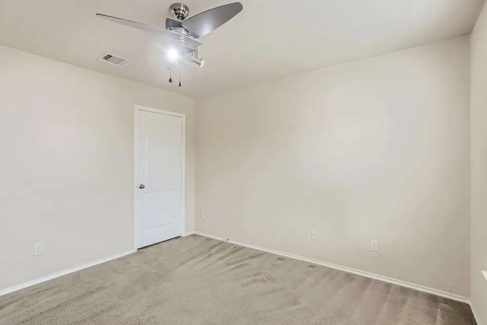 Neutral wall paint, ceiling fan with brushed nickel finish, paneled interior door, and carpeted flooring