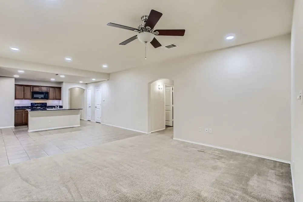 Open-concept living area featuring a ceiling fan, recessed lighting, and a kitchen with dark wood-finish cabinetry, black appliances, and a breakfast bar