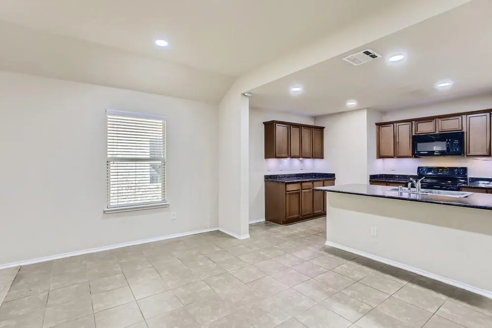 Spacious kitchen featuring dark wood cabinetry, dark countertops, black appliances, and recessed lighting