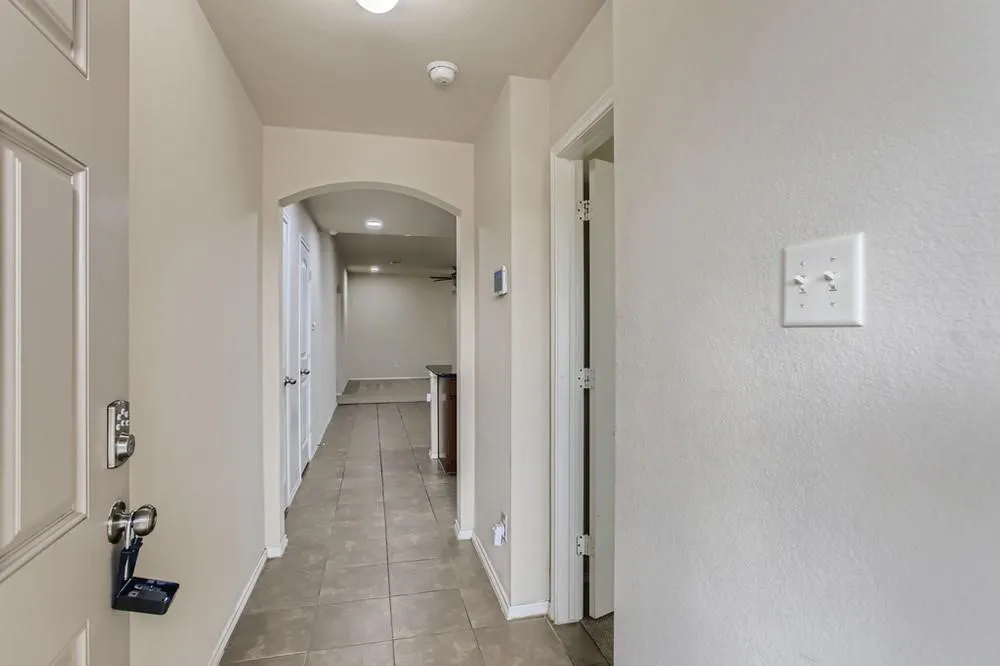 Hallway featuring tile flooring, neutral wall tones, and an arched doorway