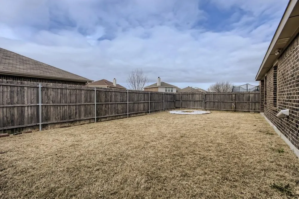 Expansive backyard featuring a full wood privacy fence and a circular stone-lined fire pit area