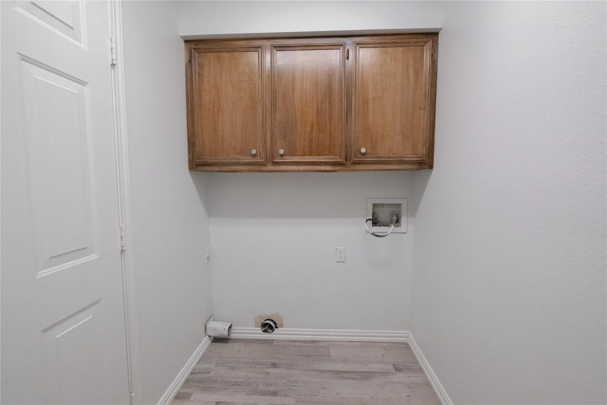 Wood-finish flooring, white walls, and wood cabinetry