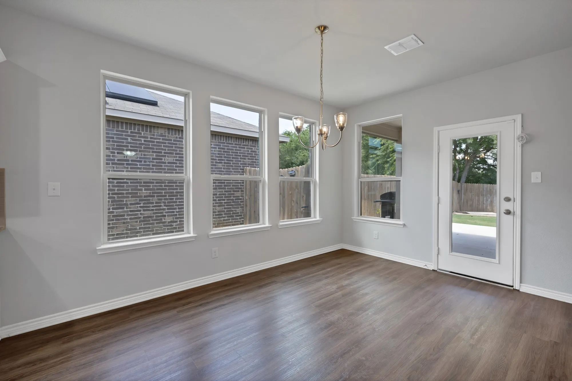Unfurnished dining area featuring dark wood-style floors, a chandelier, and healthy amount of natural light