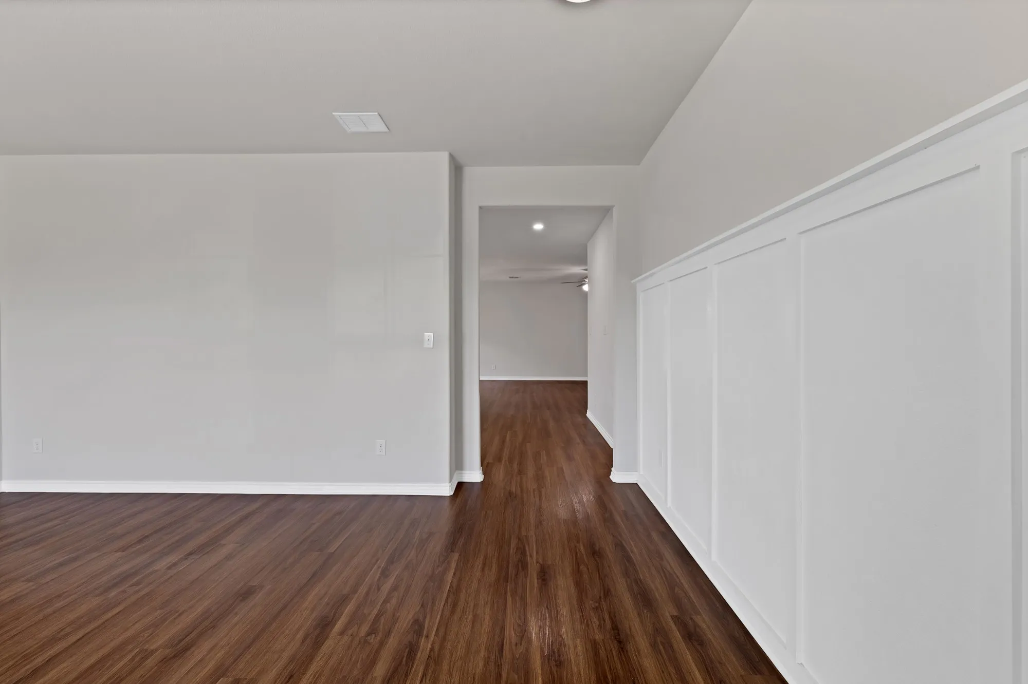 Spare room with dark wood-style flooring and baseboards