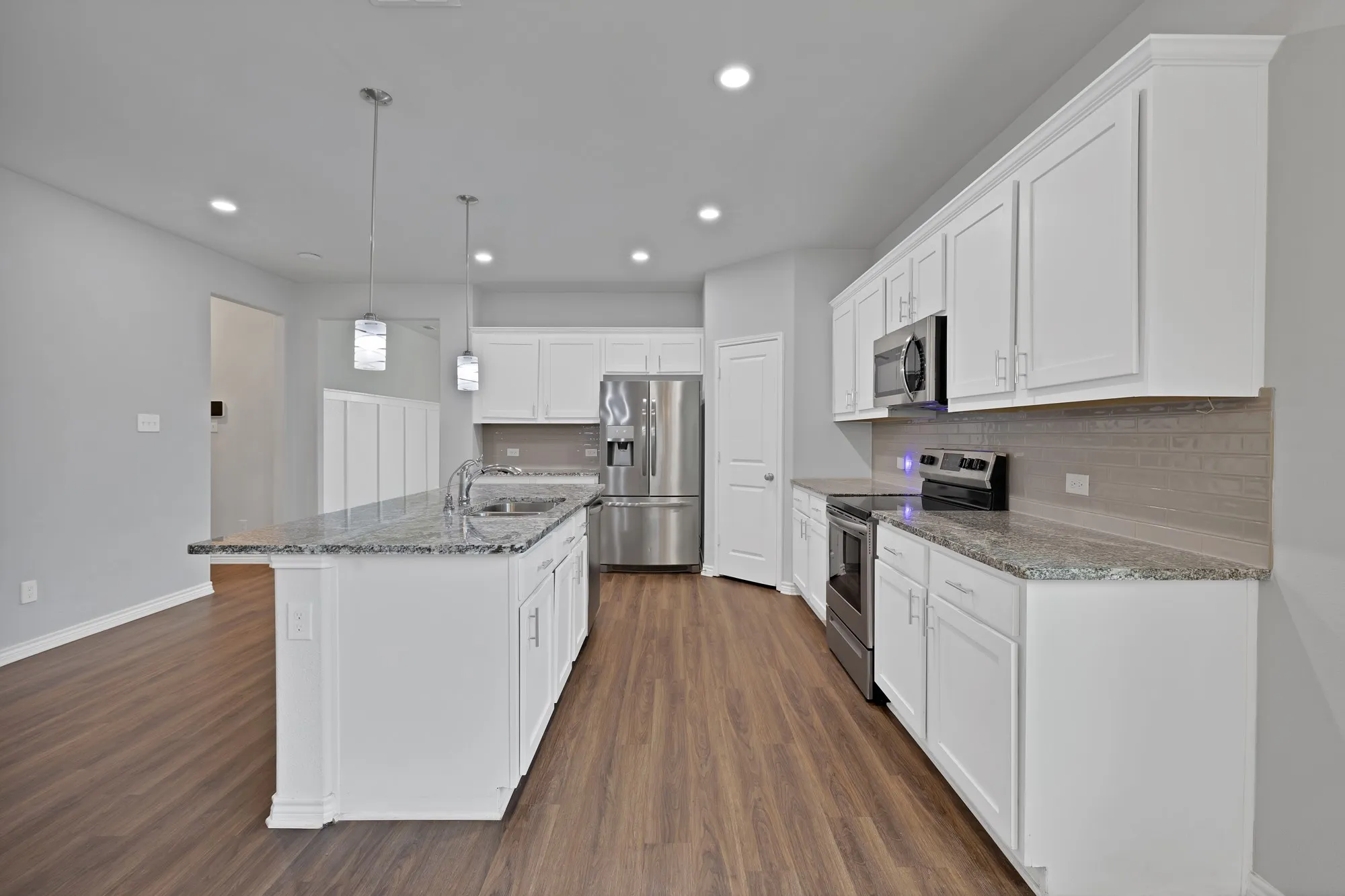 Kitchen featuring stainless steel appliances, dark wood-style flooring, decorative backsplash, white cabinetry, and recessed lighting