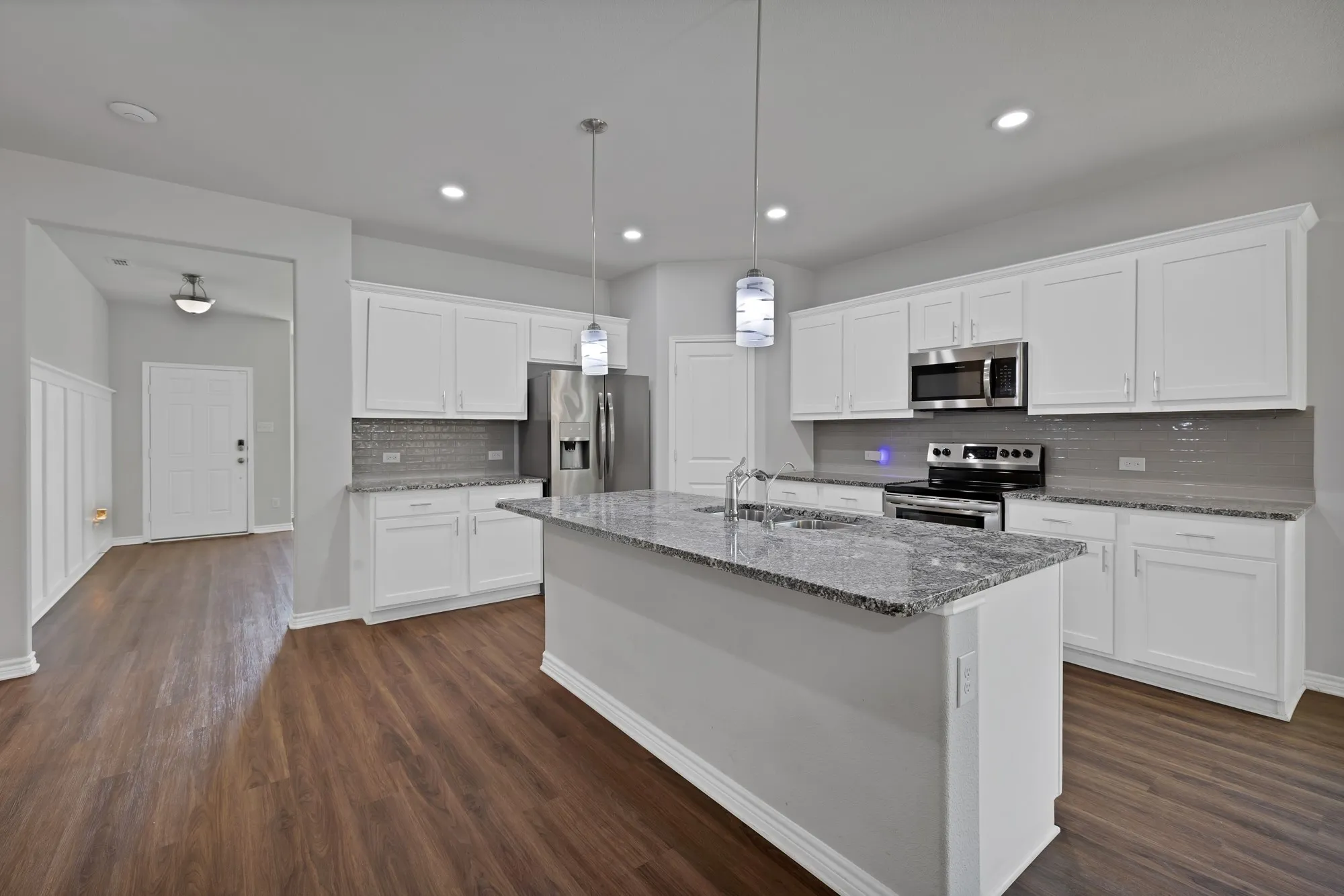 Kitchen featuring stainless steel appliances, tasteful backsplash, dark wood-style flooring, a center island with sink, and recessed lighting