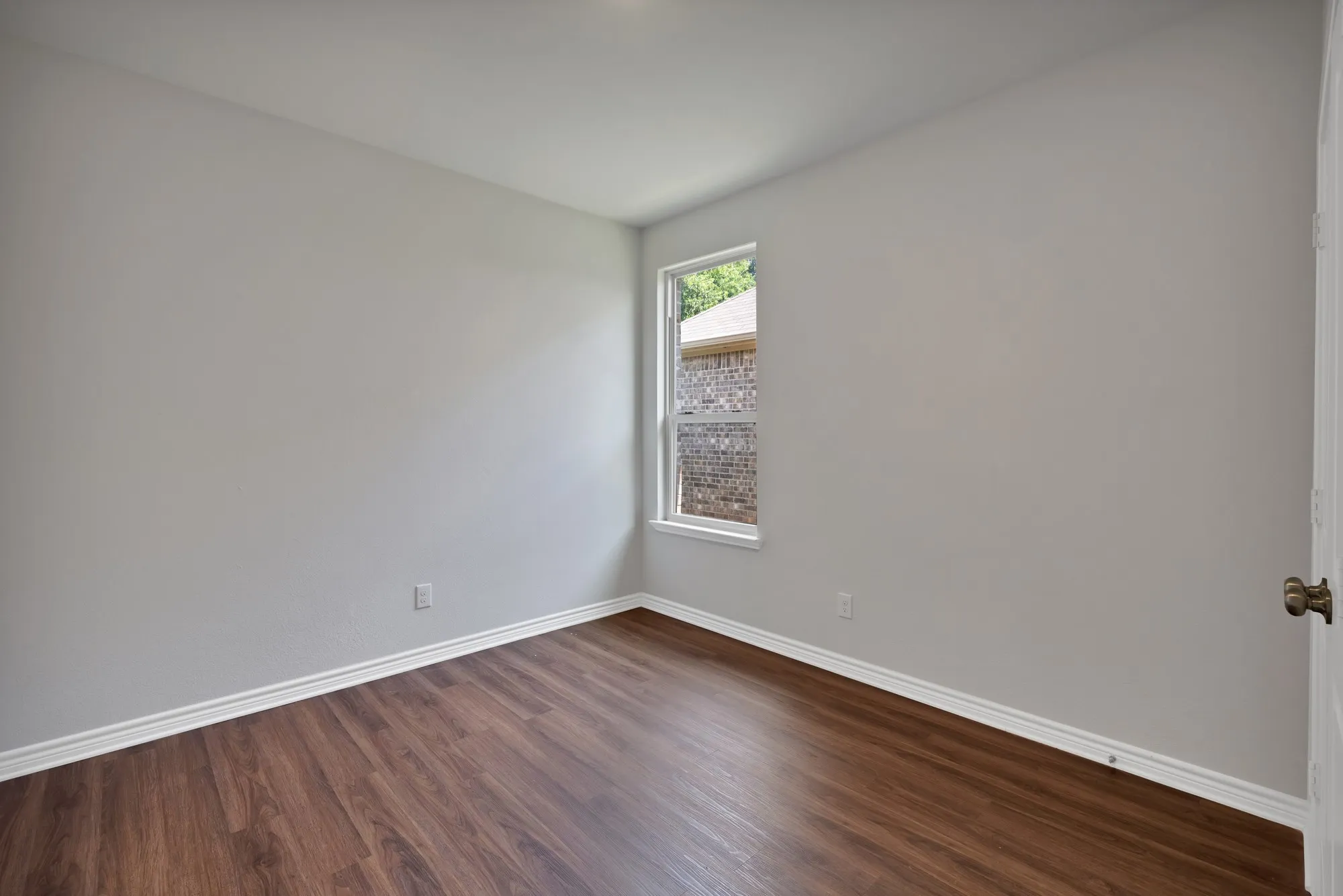 Spare room with dark wood-style floors and baseboards