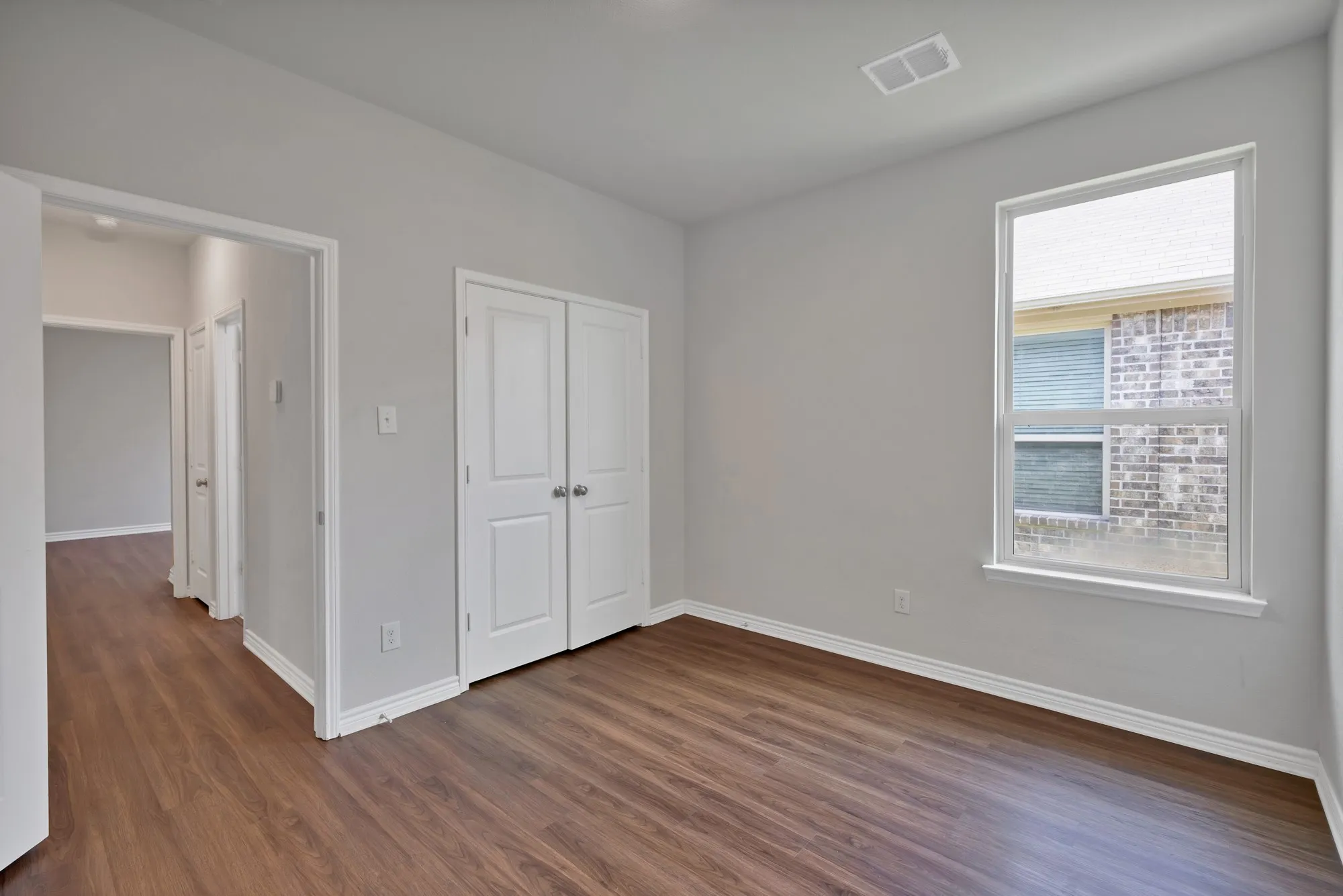 Unfurnished bedroom with dark wood-type flooring, multiple windows, and a closet