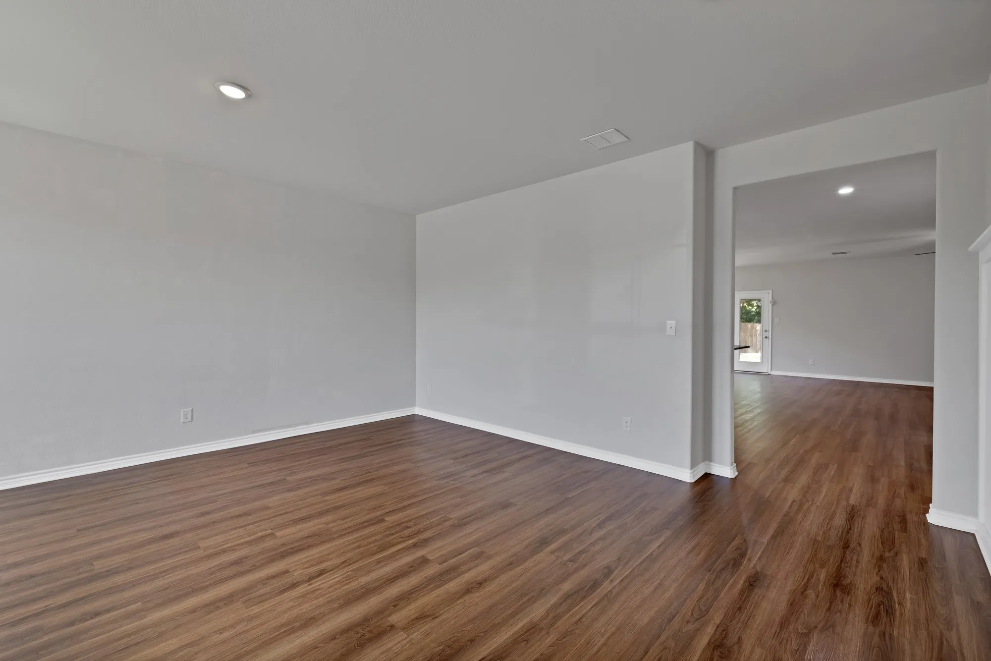 Empty room featuring dark wood-type flooring and recessed lighting