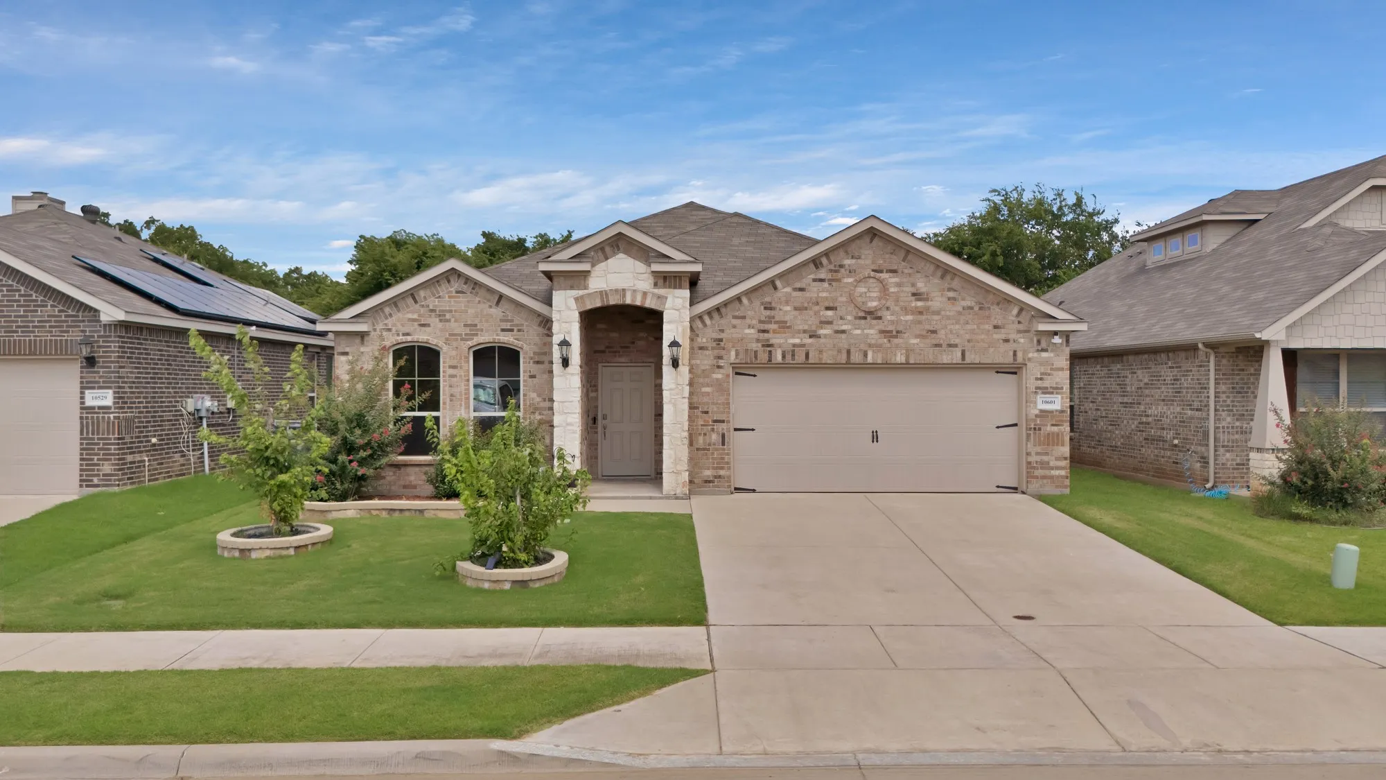 French country home with brick siding, a garage, concrete driveway, and a front yard