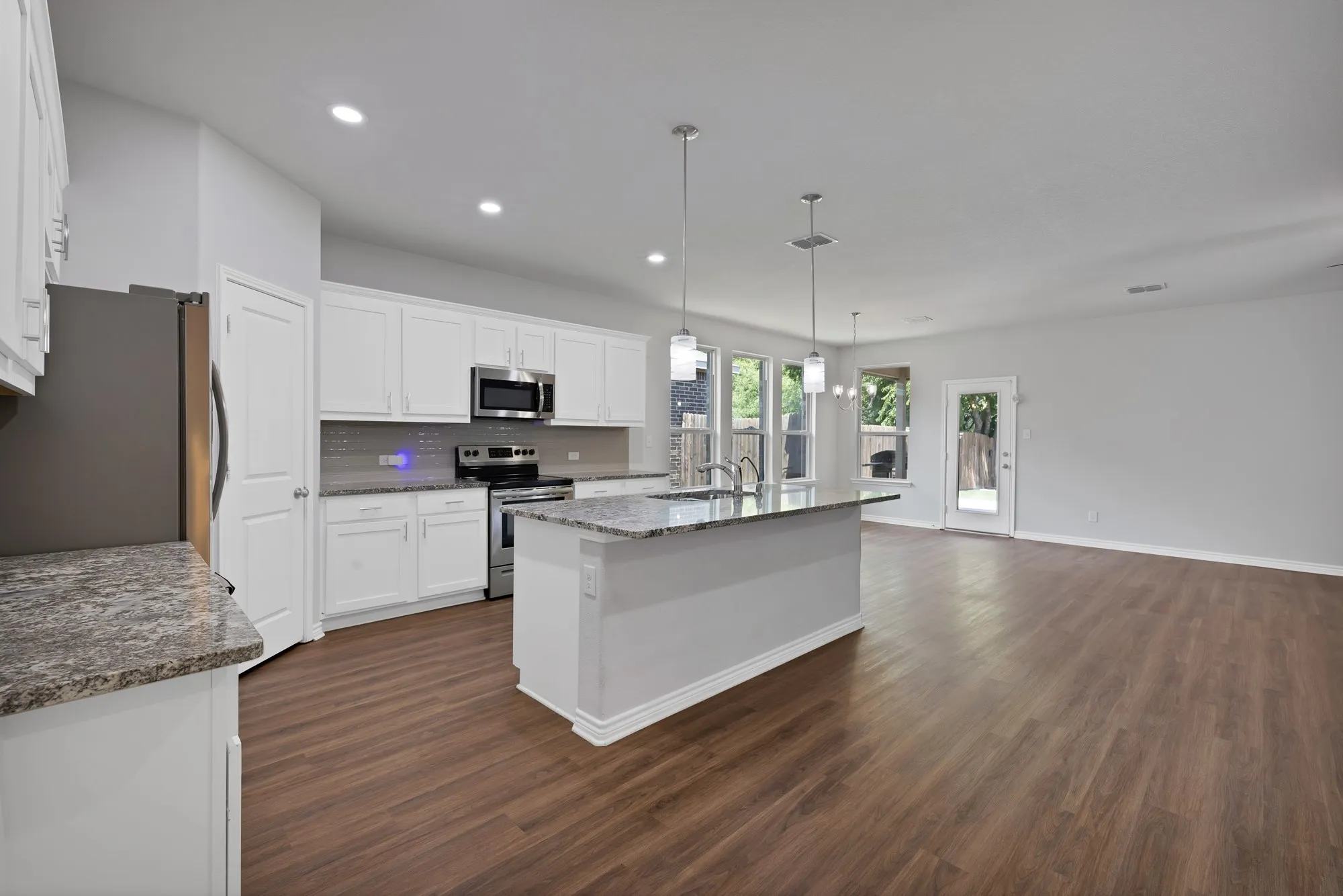 Kitchen featuring stainless steel appliances, dark wood-style floors, white cabinets, decorative backsplash, and recessed lighting