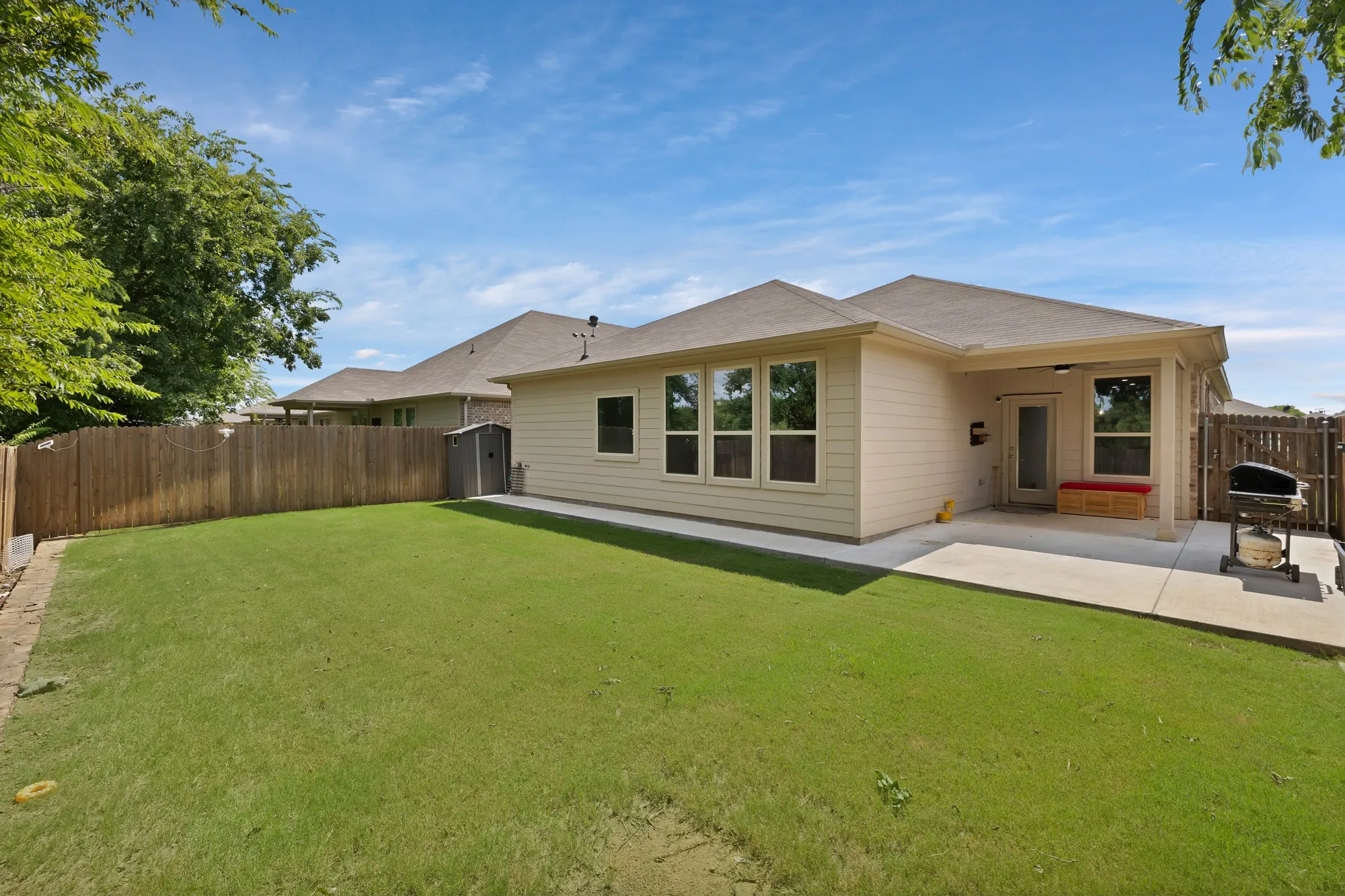 Back of property featuring a fenced backyard, a patio area, and a storage shed