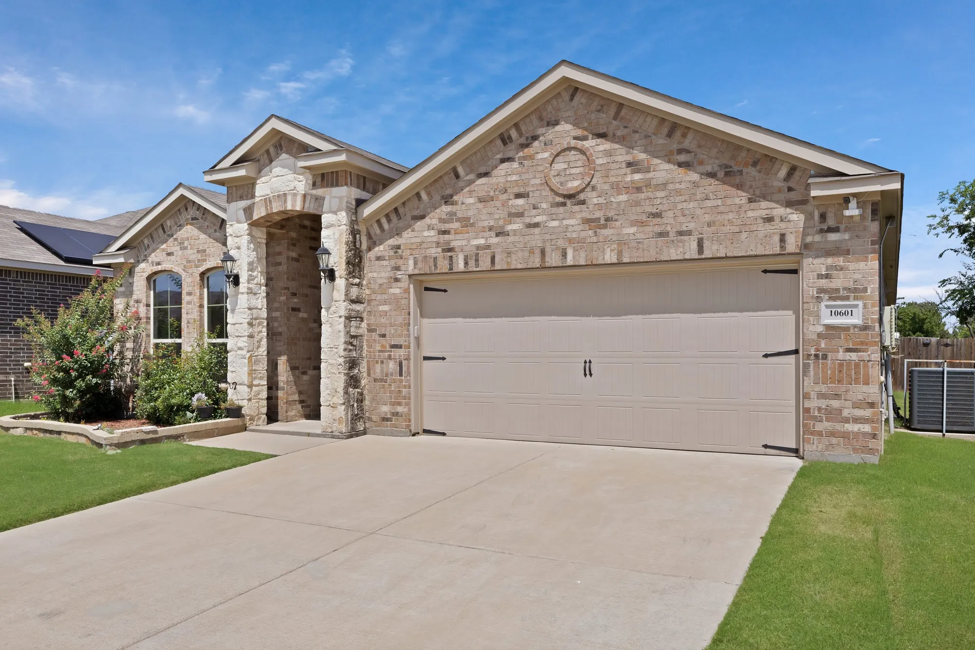 French country home with concrete driveway, an attached garage, brick siding, and stone siding