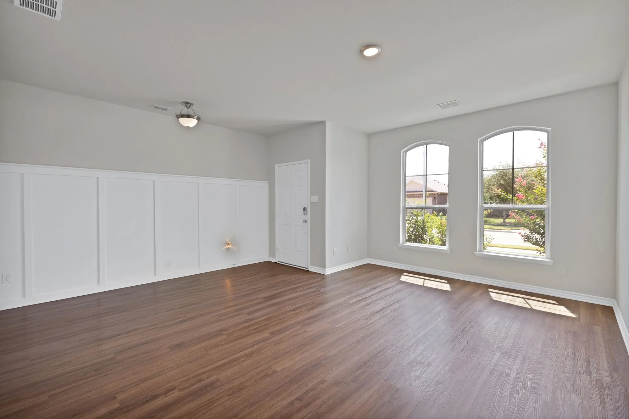 Unfurnished living room featuring dark wood-style floors and a decorative wall