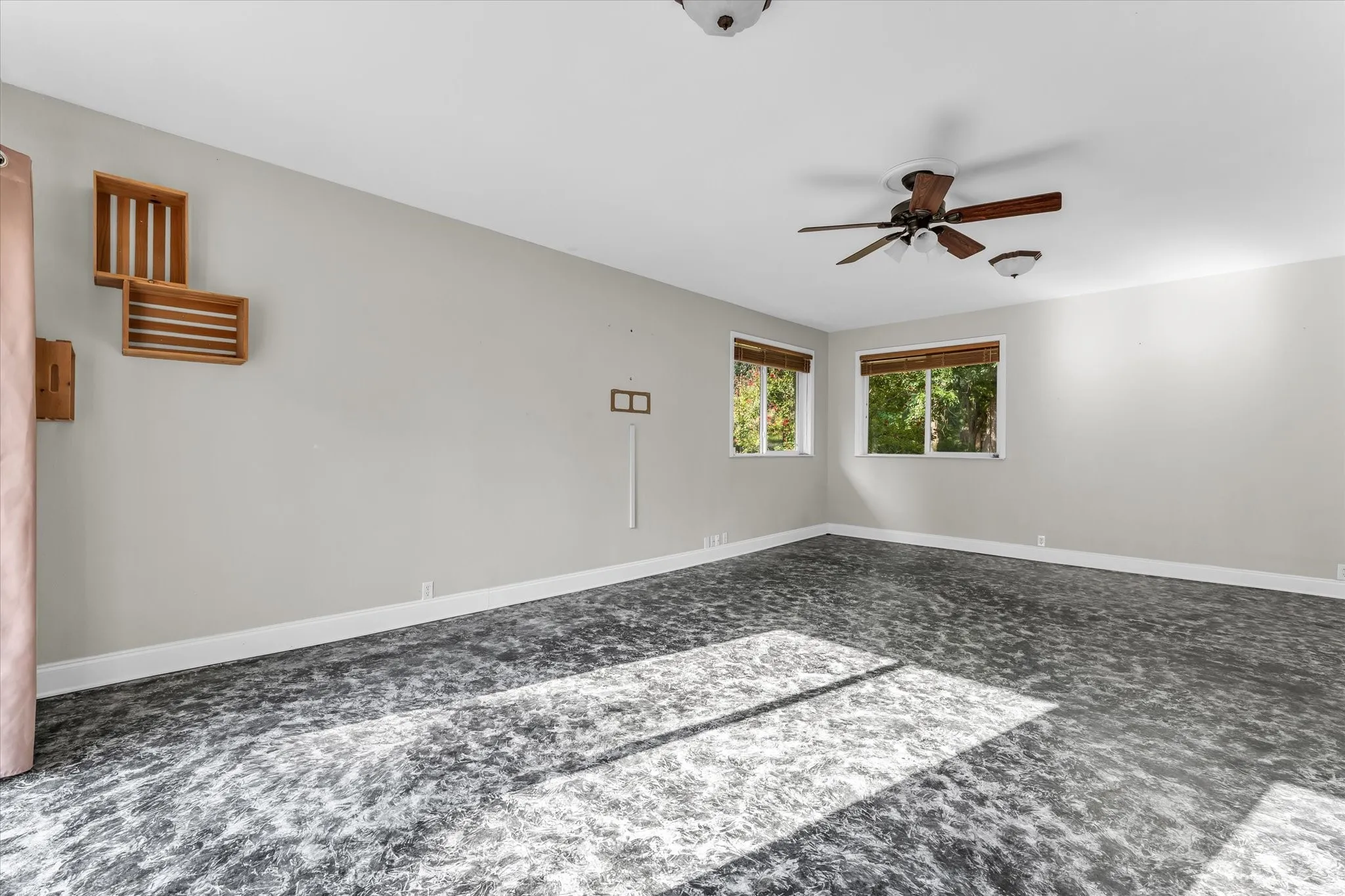 Spacious Den featuring a ceiling fan, two windows, and textured flooring