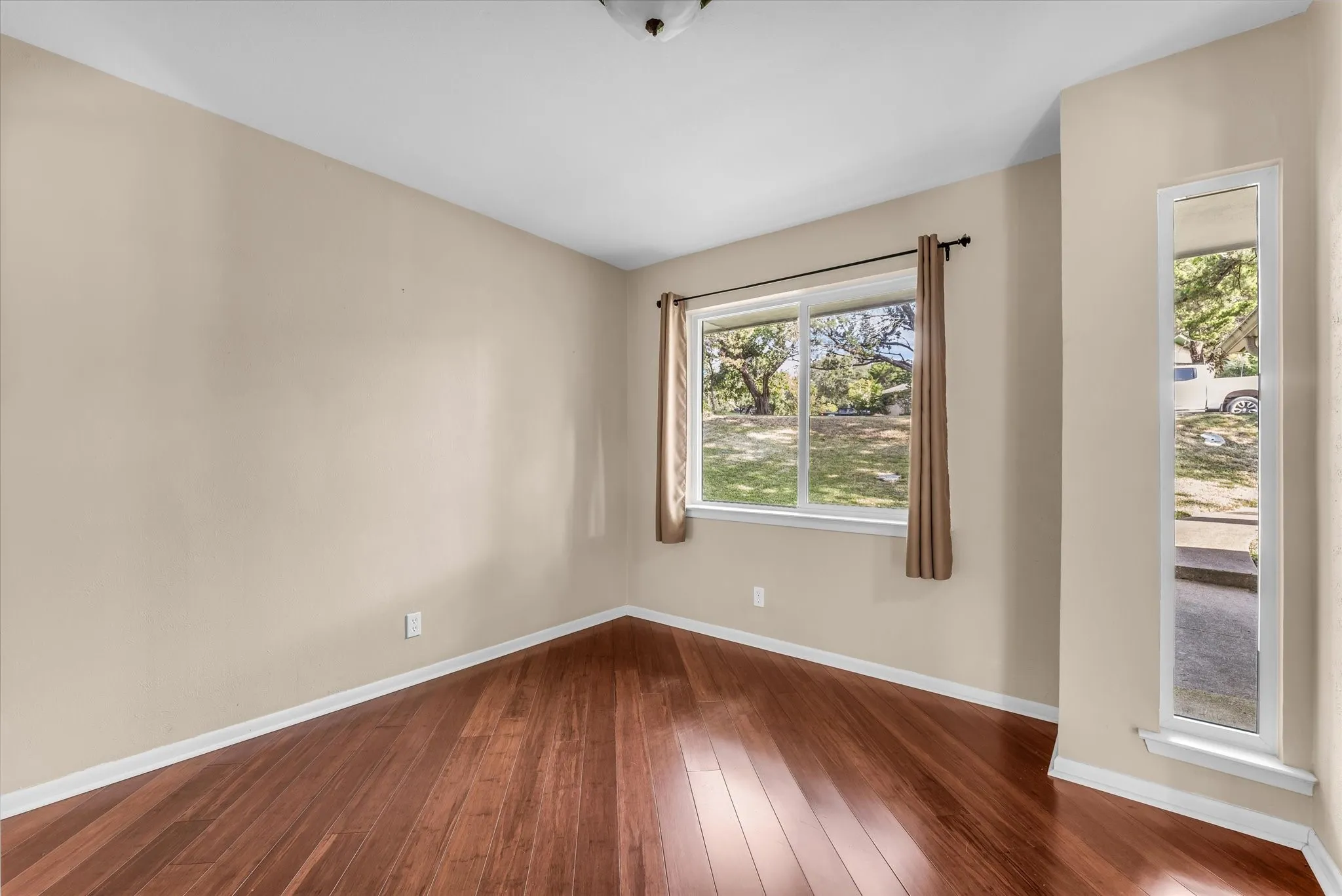 Hardwood flooring throughout, neutral wall tones, and a large window providing natural illumination
