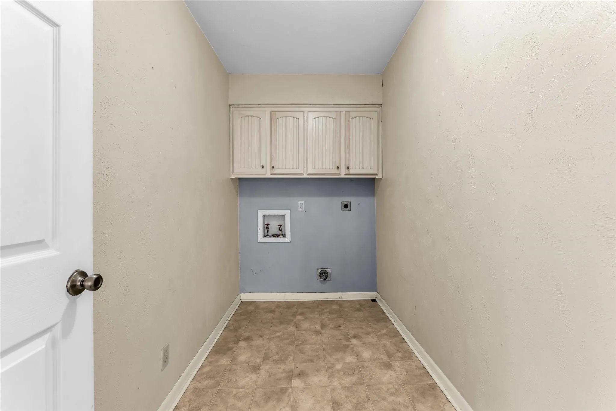 Laundry area with upper cabinetry and pre-plumbed connections for appliances