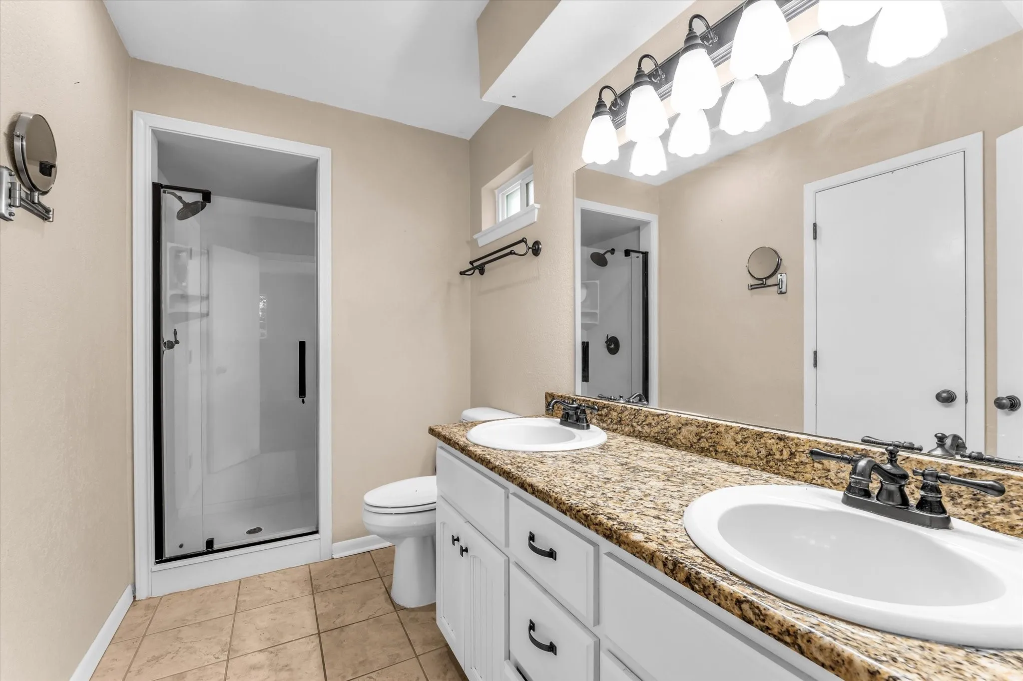 Dual vanity with granite-style countertop, dual sinks, and dark fixtures