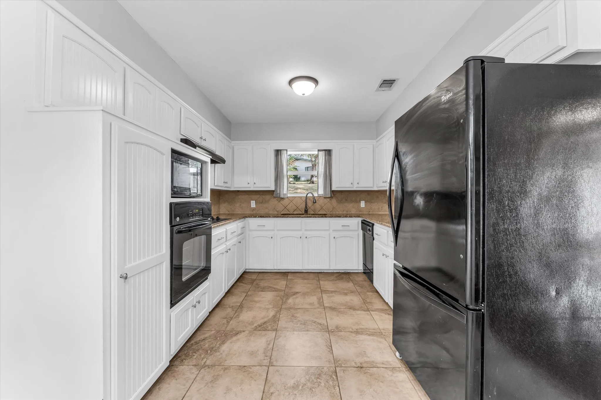 White cabinetry, built-in wall oven and microwave, and tile flooring
