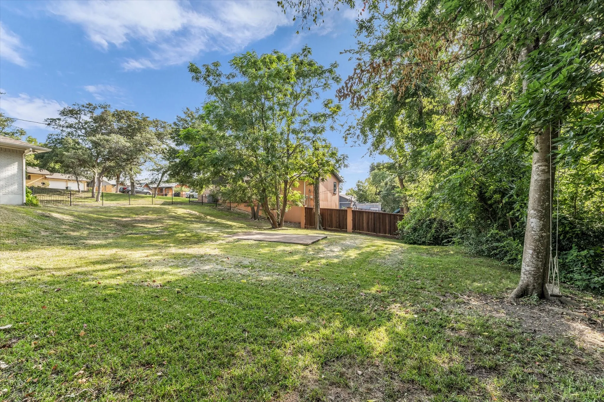 Expansive grassy yard featuring mature trees and a wood privacy fence