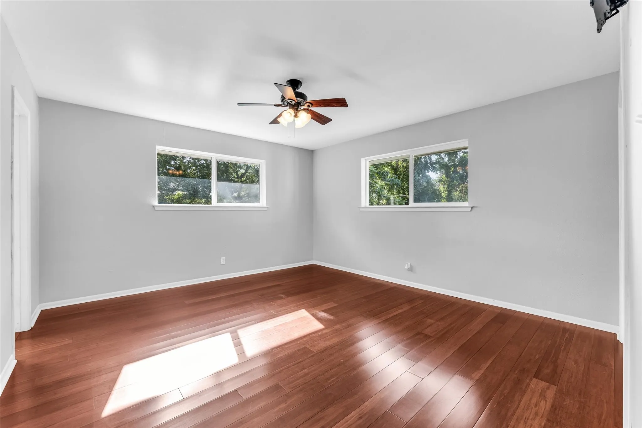 Wood-finish flooring, ceiling fan with integrated lighting, recessed closet, and light gray wall paint. Ensuite bathroom