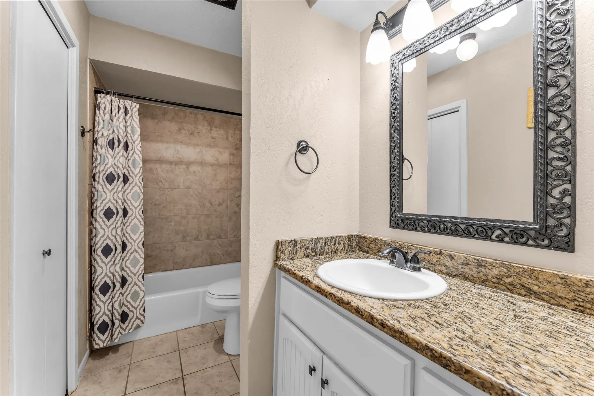 Vanity with granite countertop, integrated sink, and decorative framed mirror