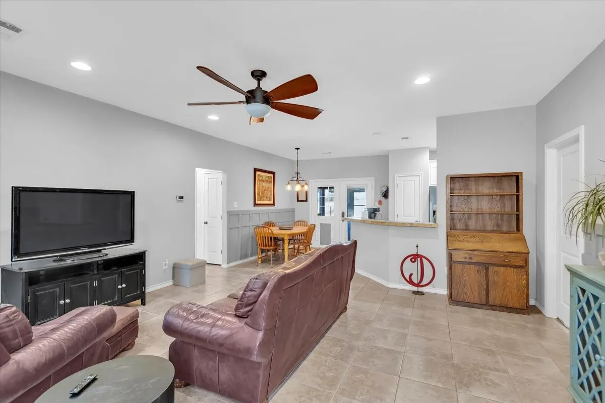 Spacious open-concept living area featuring tile flooring, recessed lighting, and a ceiling fan