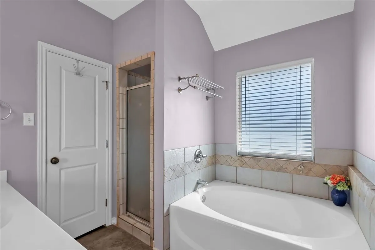 Built-in soaking tub with chrome fixtures, tiled surround, and integrated window