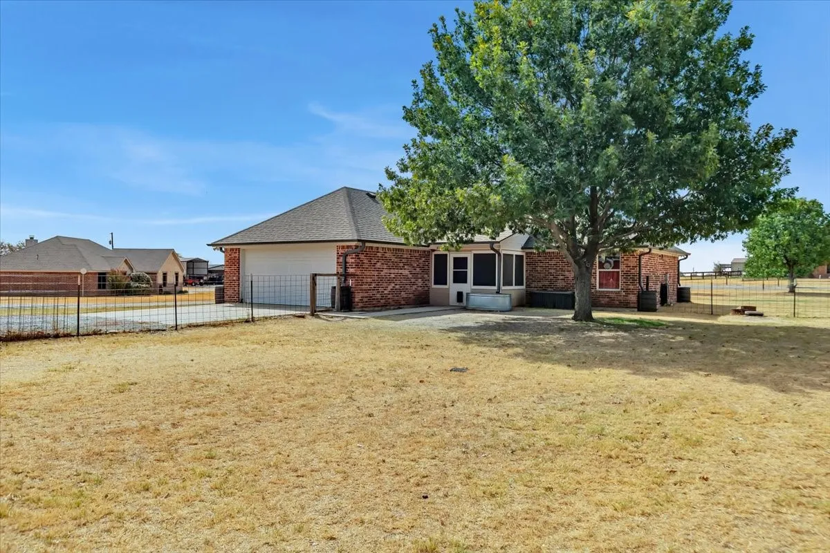 Brick exterior with a screened-in porch, attached garage, and mature trees