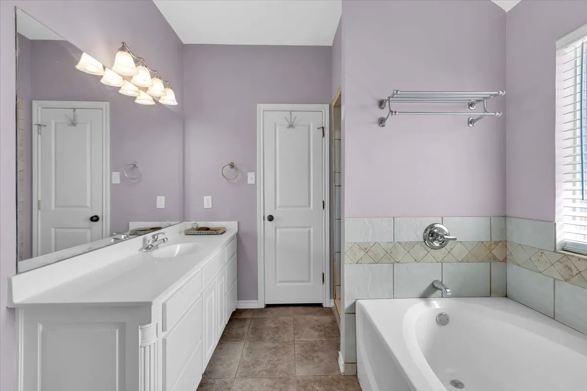 Dual sink vanity with white cabinetry, full-width mirror, and multi-light fixture