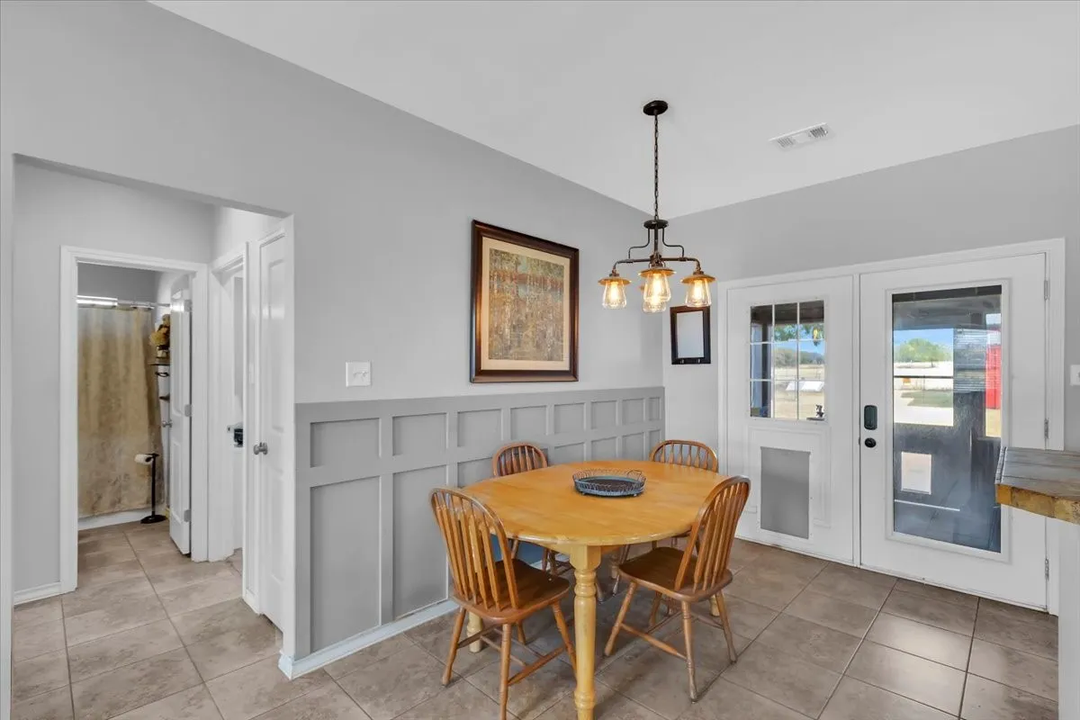 Tile flooring, wainscoting, suspended lighting fixture, and double glass-panel doors