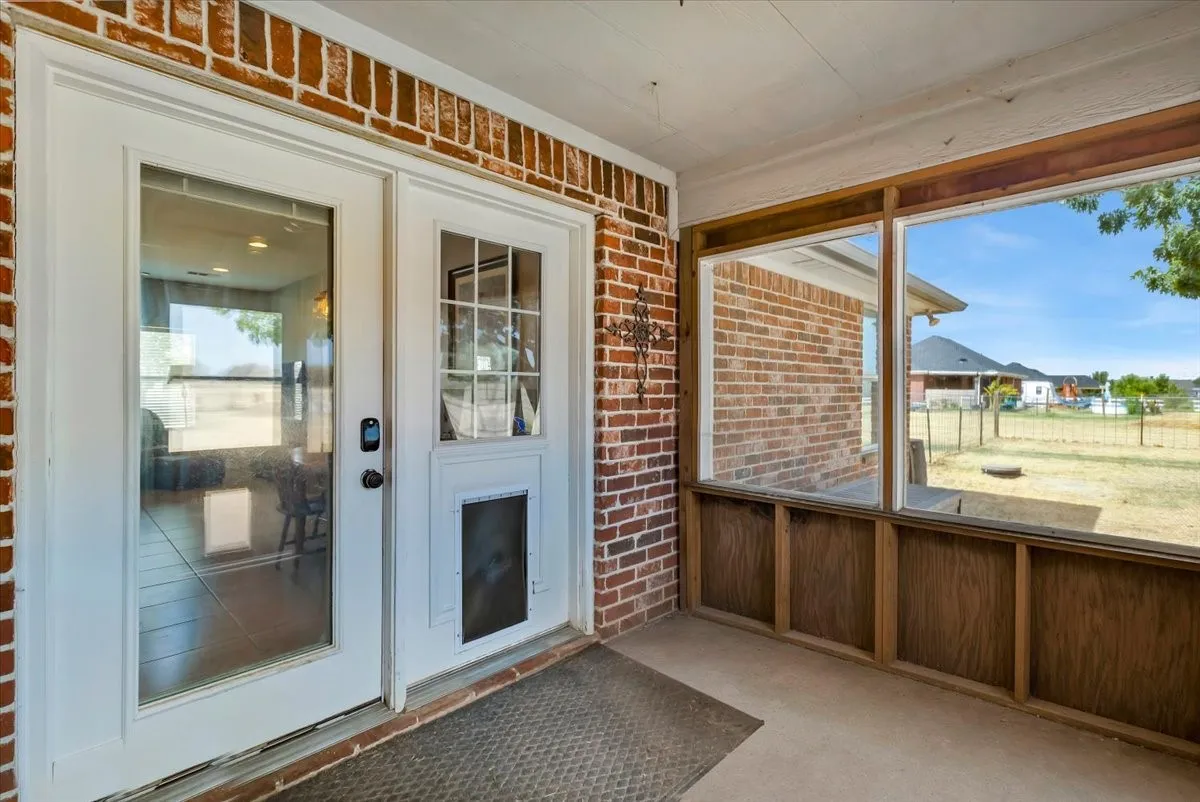 Screened-in porch featuring brick exterior, white framed doors, and large glass panels